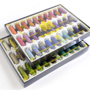 May include: Two clear plastic boxes filled with colorful spools of thread. The boxes are stacked on top of each other and have a black border. The top box has the word "WONDERFUL" printed on it in gold letters.
