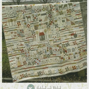 May include: A patchwork quilt titled The Goat, The Goose, & A Cow Called Bruce, featuring farm-themed illustrations of animals, tractors, windmills, and houses in muted earth tones. The quilt is composed of various squares and rectangular panels.