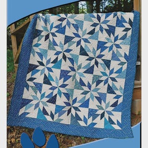 May include: A blue and white quilt with a starburst pattern. The quilt has a blue border and is displayed outdoors. The text "DEB'S CATS N QUILTS Presents: Playing Favorites" is visible. Designed by Deb Heatherly.