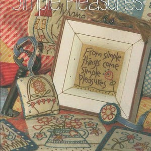 May include: A book cover with the title "Simple Pleasures" and the text "A little book of little stitches." The image includes a framed embroidery piece with the words "From simple things come simple pleasures."