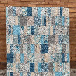 May include: A rectangular quilt featuring a patchwork design of blue, grey, and white fabric squares with floral and geometric patterns. The text SLICED BREAD, Finishes 54" x 64", and MY BESTE QUILT CO A quilt pattern by Renee Den Beste are visible.