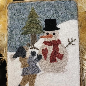 May include: A needlepoint wall hanging with a winter scene featuring a snowman with a red scarf and a child holding a gift. The text "Winter Memories" is at the bottom of the image.