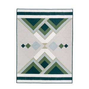 May include: A geometric quilt with a modern design. The quilt features a pattern of green, white, and gray shapes. The text "Winter Solstice" is at the top. The quilt is available in baby, throw, and queen sizes.