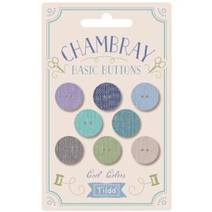 May include: A package of eight Chambray Basic Buttons in cool colors. The buttons are made of fabric and have a textured look. The package is labeled "Chambray Basic Buttons" and "Cool Colors" with the Tilda logo.