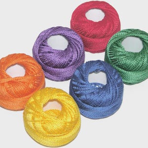 May include: A collection of six colorful spools of thread in shades of orange, yellow, purple, red, blue, and green. Each spool is tightly wound with a central hole, ideal for various crafting projects.