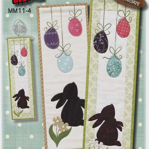 May include: A craft pattern featuring a bunny and Easter egg design. The pattern includes instructions for a 6" x 18" or 6" x 22" project, with an intermediate skill level. The design features a black bunny silhouette and hanging Easter eggs.