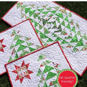 May include: A festive winter table runner and placemat set with a white background and green and red Christmas tree designs. The set includes a runner and several placemats with a red border. The text "winter table" is at the top.