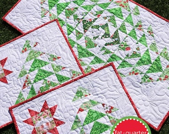 May include: A festive winter table runner and placemat set with a white background and green and red Christmas tree designs. The set includes a runner and several placemats with a red border. The text "winter table" is at the top.
