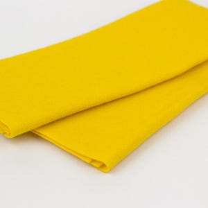 Puede incluir: Un trozo de tela de fieltro amarillo brillante doblado.