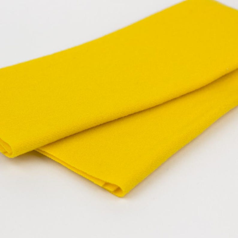 Puede incluir: Un trozo de tela de fieltro amarillo brillante doblado.