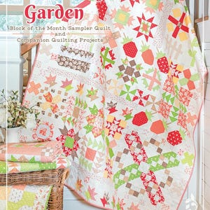 May include: A colorful quilt with a strawberry and star pattern, draped over a staircase. The quilt features red, green, and peach-colored blocks. The text "Strawberry Garden" is visible at the top, with additional text below.