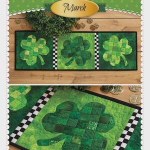 May include: A patchwork accent runner featuring three green shamrock designs. The runner has a black border and a checkered pattern on each end. The text "Shamrocks March" is displayed at the top. The product is from Shabby Fabrics.