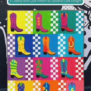 May include: A colorful quilt pattern featuring rows of cowboy boots in various colors and designs. The quilt is titled "Boot Tapping Blvd" and is a pattern by Sassafras Lane Designs. The boots are in shades of purple, pink, yellow, orange, and blue.
