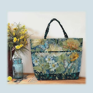 May include: A floral market tote bag with a braided handle. The bag features a botanical print with butterflies and flowers in shades of blue, green, and yellow. The tote is 14 inches high, 20.5 inches wide, and 6 inches deep.