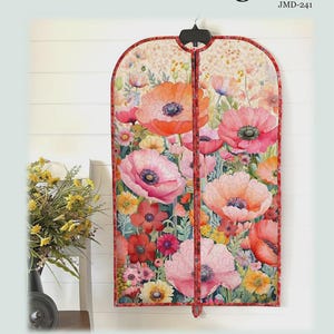 May include: A garment bag featuring a vibrant floral print with red, pink, and orange poppies on a light background. The bag has a zippered front and a hanger at the top. Text reads: Playing with Panels Garment Bag, JMD-241, Finished Size 24 inches wide by 38.5 inches high.