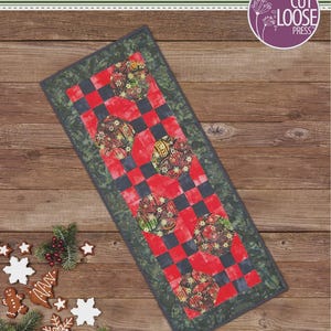May include: A rectangular table runner titled Snowball Runner by Anita Covert, featuring a red and black checkered pattern with circular floral motifs and a dark green border. The text 17 inches by 42 inches is printed at the bottom of the image.
