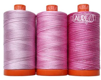 May include: Three spools of pink thread, from lightest to darkest, with the Aurifil logo on each spool.