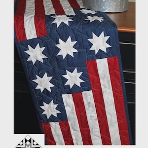 May include: A Stars & Stripes runner, 13.5" x 41.5", features a blue field with white starbursts and red and white stripes. The text "Stars & Stripes" and "Creek Side Stitches" are visible. The runner is a patriotic home decor item.