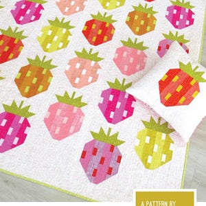 May include: A quilt and pillow pattern titled BERRY SEASON by Elizabeth Hartman featuring a grid of stylized strawberry blocks in shades of red, pink, orange, and yellow on a white background with green stems, created using conventional patchwork.