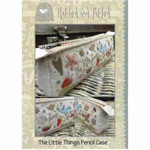 May include: A white fabric pencil case with a zipper closure. The case is decorated with colorful embroidery featuring a bird, flowers, strawberries, and the text "The Little Things".