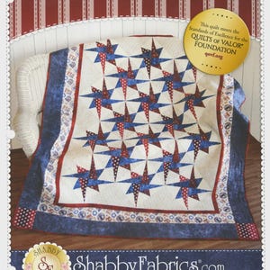 May include: A patriotic quilt with a star pattern in red, white, and blue. The quilt features a white background with alternating red and blue starburst designs. The border is a dark blue with red polka dots. The text "PATRIOTIC STARRY PATH" is at the top.