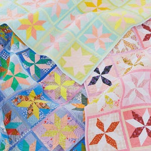 May include: A collection of colorful handmade quilts with starburst patterns. The quilts feature a variety of colors, including blue, pink, yellow, and green. Each quilt is made of squares with star-shaped designs.