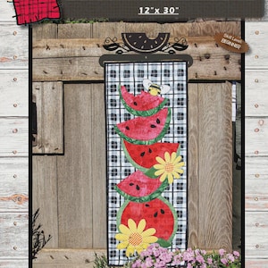May include: A decorative wall hanging featuring the text "JUICY WATERMELONS" and dimensions of 12" x 30". The design includes stacked watermelon slices, a bee, and yellow flowers on a black and white checkered background. The skill level is beginner.