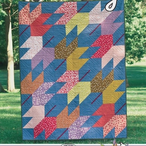 May include: A quilt featuring a blue background with a repeating pattern of multi-colored leaf shapes in red, yellow, orange, and purple floral and polka dot prints. The text Falling, Running Doe Quilts, and For Villa Rosa Designs is visible.