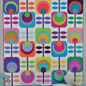 May include: A colorful quilt with a retro floral design. The quilt features large, stylized flowers in vibrant shades of orange, pink, blue, green, and purple, set against a white background. The words "Flower Power" are at the top.