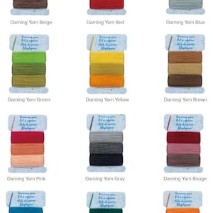 May include: A collection of darning yarn spools in various colors, including beige, red, blue, green, yellow, brown, pink, gray, rouge, lake, emerald, and orange. Each spool is labeled with the yarn color name.