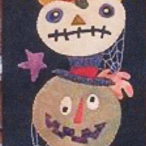 May include: A Halloween-themed wall hanging featuring stacked, smiling jack-o'-lanterns in shades of orange, green, and white. The design includes stars and spiderwebs against a dark blue background. The bottom has vertical stripes.