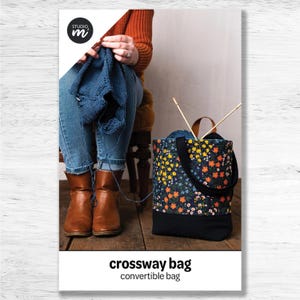 May include: A floral print tote bag with a black base and handles, filled with yarn and knitting needles. The bag is next to a person knitting with blue yarn. The image includes the text "crossway bag" and "convertible bag".