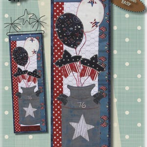 May include: A patriotic fabric wall hanging featuring a milk can design with balloons and flags. The design includes a milk can with a star, balloons, and flags. The dimensions are 6 inches by 18 inches.