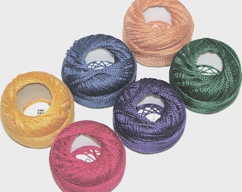 May include: A collection of six spools of colorful embroidery thread. The spools are in shades of gold, pink, purple, blue, green, and peach. Each spool has a central hole, revealing the inner structure of the thread.
