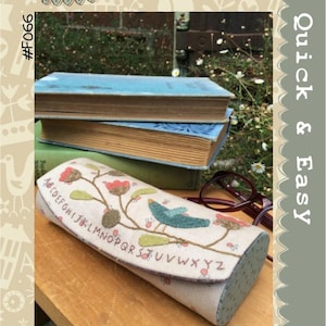 May include: A fabric case with a floral and bird design, with the text "Briar Rose Case". The case is beige with a floral and bird design in red, green, and blue. The case is on a wooden surface with books in the background.