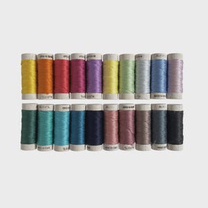 May include: A collection of colorful Aurifil thread spools. The spools are arranged in two rows, showcasing a variety of vibrant colors, including yellow, orange, red, pink, purple, green, blue, and black. Each spool is labeled with "MADE IN ITALY".