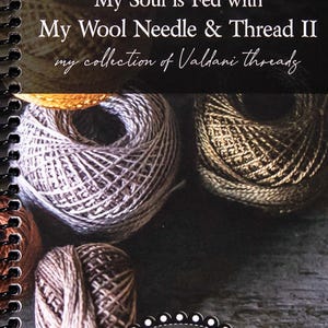 May include: A book titled "My Soul is Fed with My Wool Needle & Thread II my collection of Valdani threads" by Primitive Gatherings by Lisa Bongean. The cover features a close-up of several skeins of yarn in various shades of brown and beige.