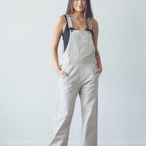 May include: Beige overalls with adjustable straps, a bib pocket, and side pockets. The overalls are part of a sewing pattern called "Riley Overalls" with sizes 0-18. The text "TRUE BIAS" is at the bottom.