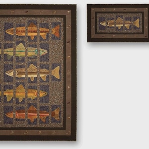 May include: A rectangular quilt with a fish design. The quilt features a brown border and a grid pattern with fish in shades of orange, yellow, and green. A smaller matching piece is also present.