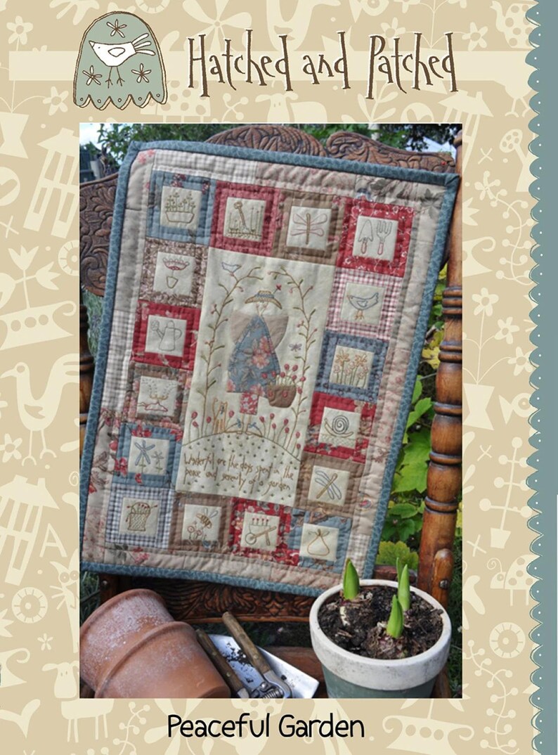 May include: A quilted wall hanging with a patchwork design featuring a variety of embroidered images, including a woman in a garden, birds, flowers, and a watering can. The text "Underneath are the days spent in the peace and serenity of your garden" is embroidered on the wall hanging. The wall hanging is displayed on a wooden chair with a potted plant in front of it.