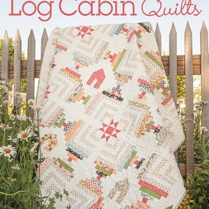 May include: A cream-colored Log Cabin quilt with various geometric patterns and a star design. The quilt features a variety of colors, including red, green, and beige. The cover of the book "Creative Log Cabin Quilts" is visible in the image.