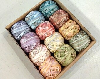May include: A box of 12 colorful balls of embroidery floss. The floss is arranged in a rainbow pattern, with the colors ranging from blue to orange.
