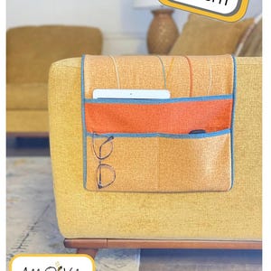 May include: A Clever Couch Caddy in shades of orange, blue, and yellow, with pockets for storage. The caddy is attached to a yellow couch. The image includes the text "Serger Pattern" and "Clever Couch Caddy".