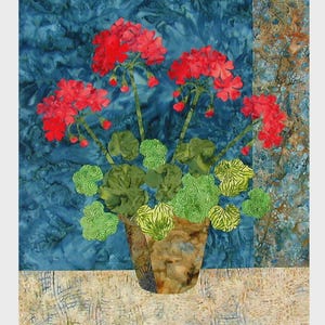 May include: A fabric art piece featuring a vase of red geraniums with green leaves against a blue background. The text "Geraniums" is at the top. The finished quilt size is approximately 20" x 22".
