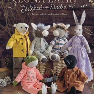 May include: Book cover featuring the title "LUNA LAPIN Stitched with Kindness" and several plush animal characters. The characters include a bear in a yellow coat, a donkey in a gray outfit, a donkey in a striped shirt, a rabbit in a purple dress, a frog in a pink outfit, and a mole in a brown coat.