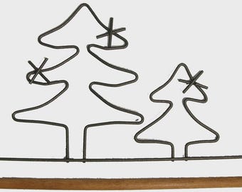 May include: A decorative metal Christmas tree-shaped towel rack. The rack features two stylized trees with star accents, crafted from dark metal. A wooden dowel serves as the towel bar, adding a natural contrast to the design.