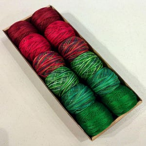 May include: A box of 10 spools of embroidery floss in red, green, and multi-colored patterns.