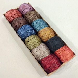May include: A box of 10 balls of embroidery floss in various colors, including red, brown, blue, green, and beige.