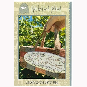 May include: A brown and beige patchwork fabric tote bag with a handle. The bag has a rectangular embroidered patch with the text "Listen to the Earth..." and a stylized image of a rabbit hopping through a field of flowers. The bag is labeled "Listen to the Earth Bag" at the bottom.