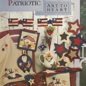 May include: A patriotic-themed display featuring various handcrafted items. Includes star-shaped ornaments, a banner of American flags, and decorative pieces with Uncle Sam imagery. The text "EASY DOES IT PATRIOTIC" and "ART-TO HEART" are visible.